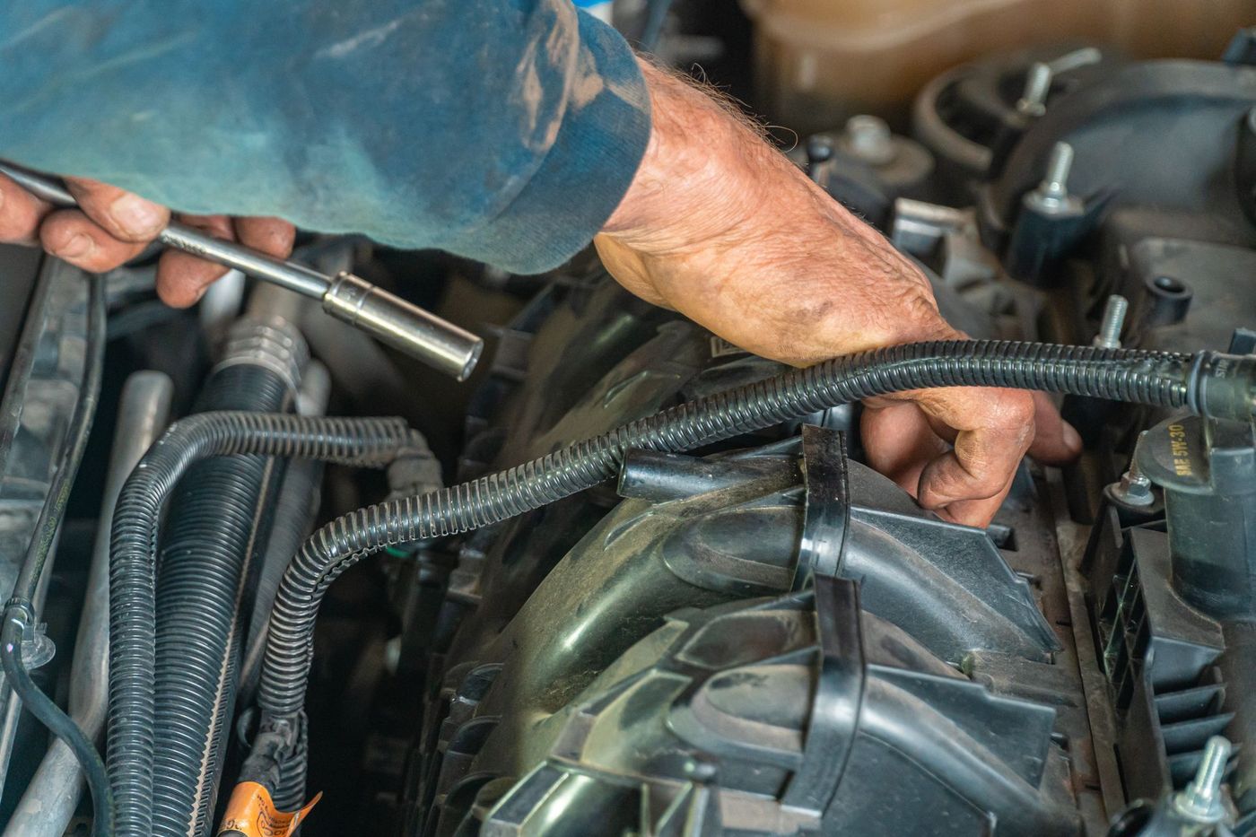 Hands using a socket wrench in a car engine bay